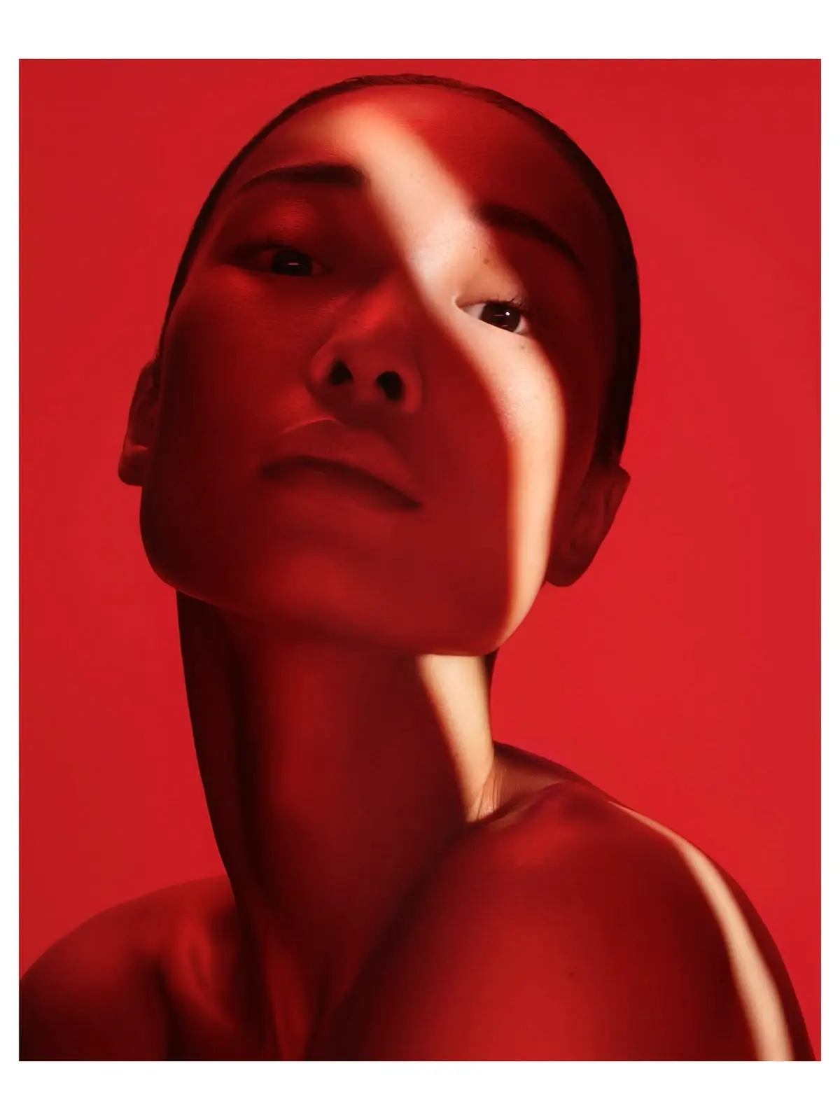 Editorial portrait of a woman illuminated by deep red light with a bright diagonal beam crossing her face